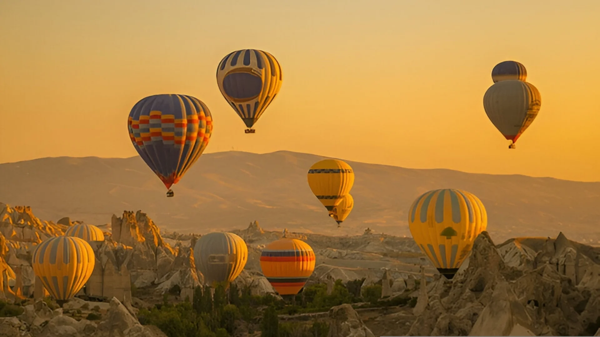 Hot air balloons flying over Cappadocia valleys at sunrise with fairy chimneys landscape